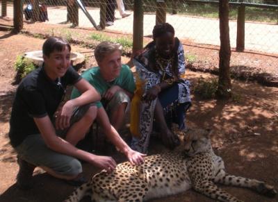 2 young friends with Maasai girl petting Cheetah